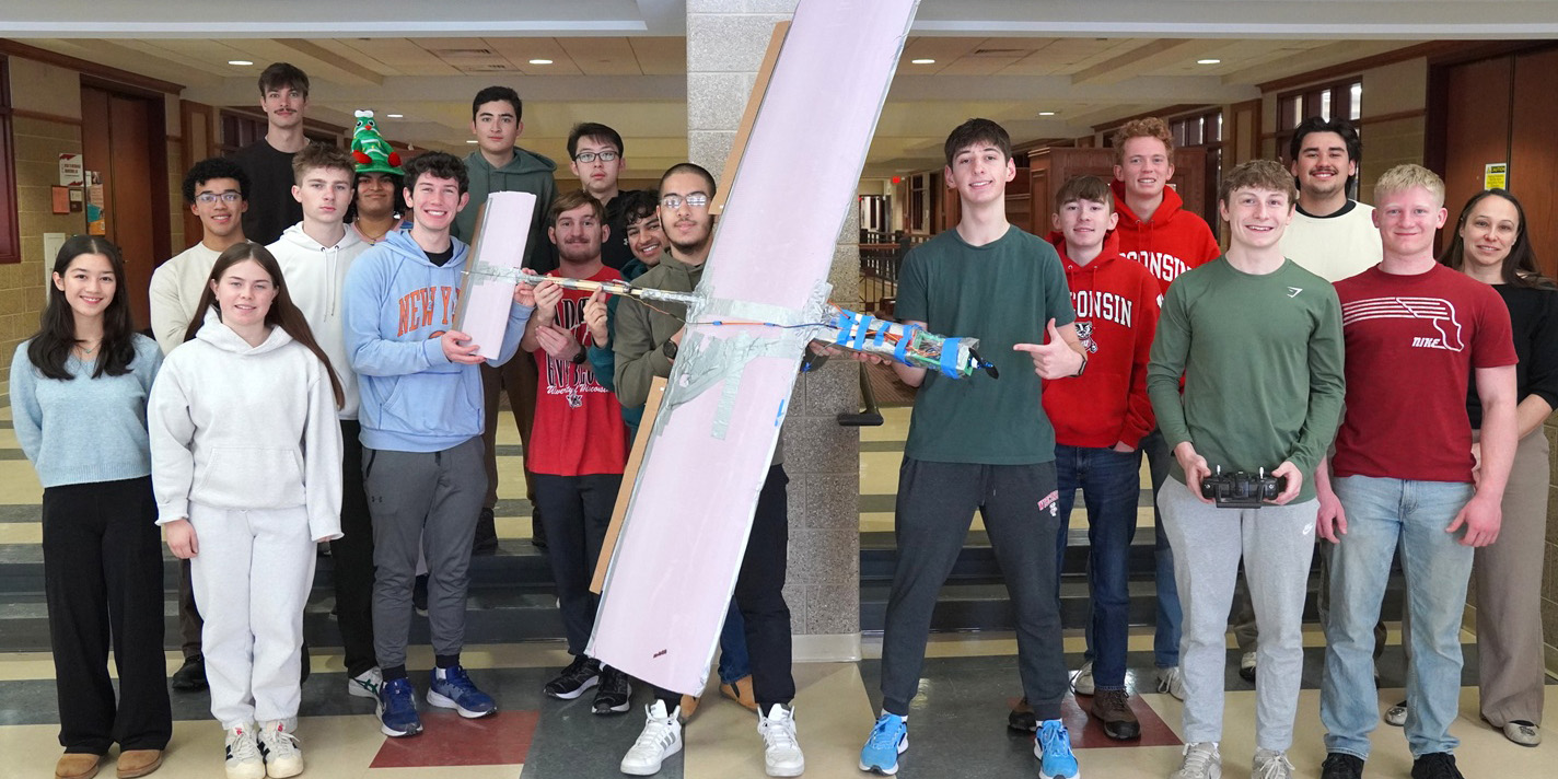 Students pose for a picture with their model airplane