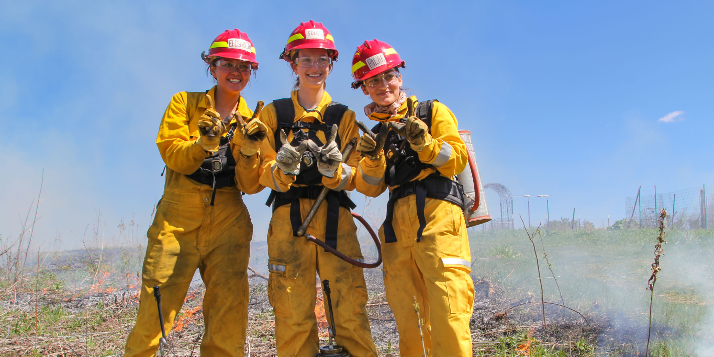 Students shown participating in an outdoor activity likely related to a controlled burn